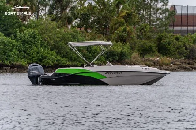 Slide: The Image of 2023 Starcraft SVX 231 OB DH boat on a calm lake with lush greenery. - 1
