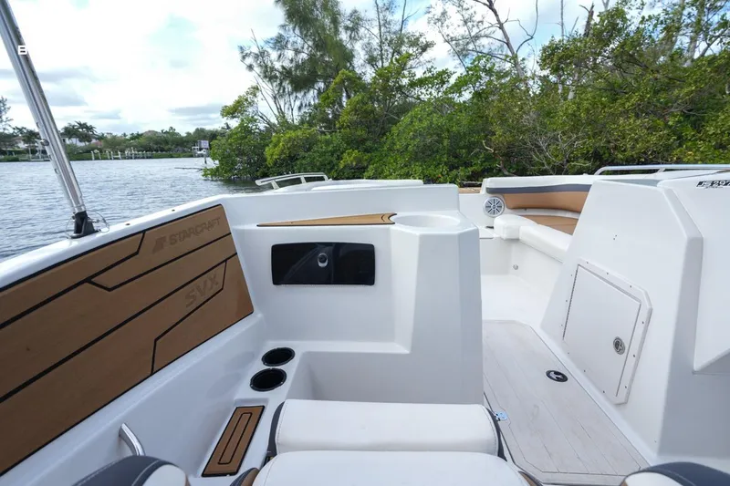 Slide: The Image of 2023 Starcraft SVX 210 boat interior with wood accents, near lush greenery and water. - 9
