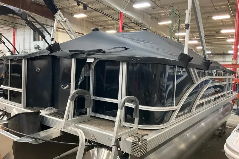 Slide: The Image of 2025 Bennington 21 SF pontoon boat with black canopy in indoor showroom. - 10