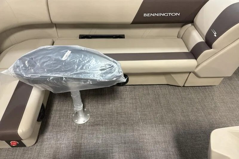 Slide: The Image of 2025 Bennington 21 SF boat interior with beige and brown seating, covered table, and carpeted floor. - 12