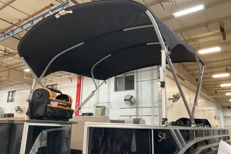 Slide: The Image of 2025 Bennington 21 SF boat with black canopy in a warehouse setting. - 8