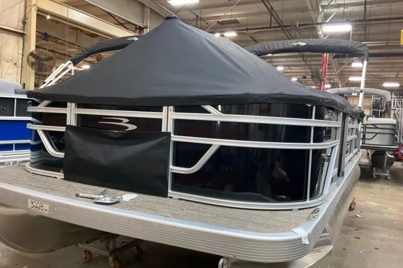Slide: The Image of 2025 Bennington 21 SF pontoon boat with black cover in a warehouse setting. - 9