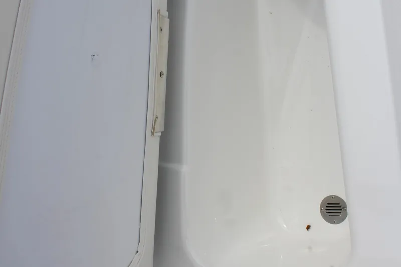 Slide: The Image of Storage compartment in 2026 Tahoe T16 boat, featuring a drain and white interior. - 16