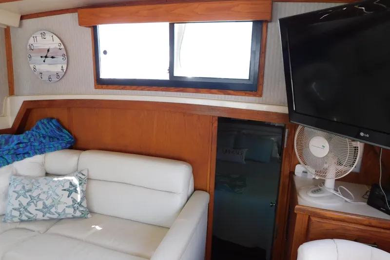 Slide: The Image of Interior of 1987 Mainship 40 DC yacht with white sofa, wall clock, and TV. - 22