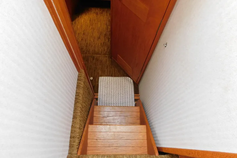 Slide: The Image of Staircase inside 1987 Mainship 40 DC yacht with wooden steps and carpeted flooring. - 28