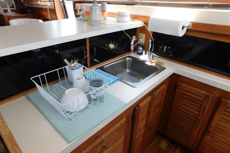 Slide: The Image of 1987 Mainship 40 DC yacht kitchen with sink, dish rack, and wooden cabinets. - 31