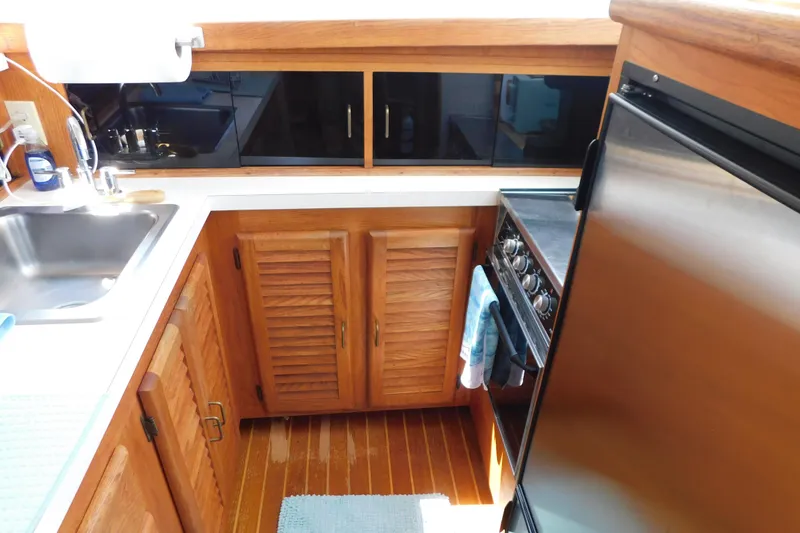 Slide: The Image of 1987 Mainship 40 DC yacht kitchen with wooden cabinets, stainless steel appliances, and sink. - 32
