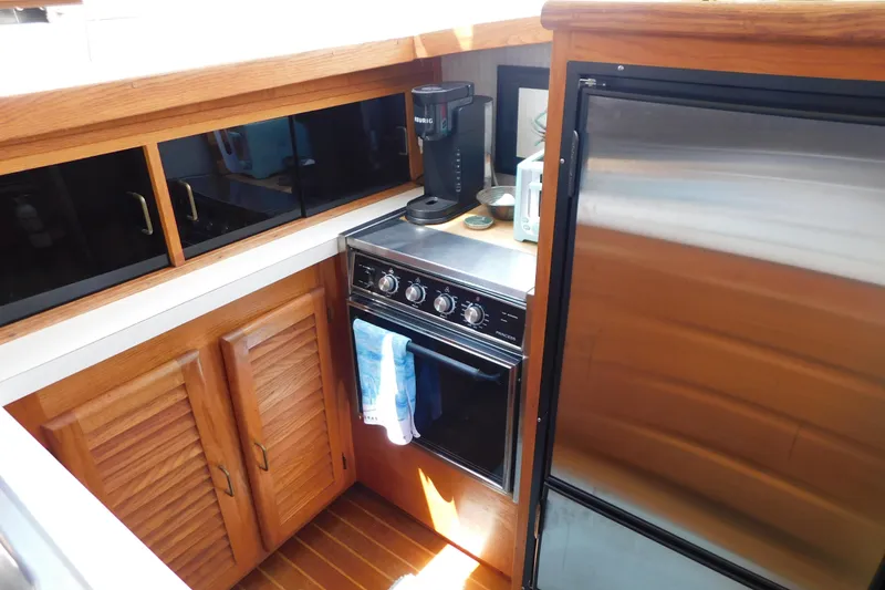 Slide: The Image of 1987 Mainship 40 DC yacht kitchen with stove, fridge, and wooden cabinets. - 33