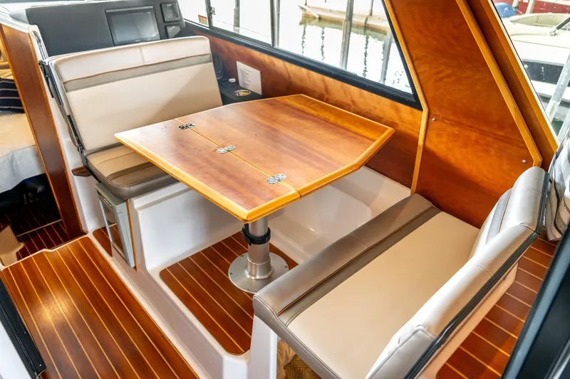 Slide: The Image of 2020 Cutwater C28 interior with wooden table and cushioned seating. - 19