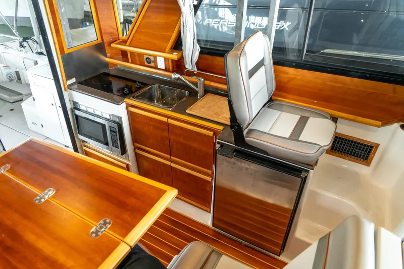 Slide: The Image of 2020 Cutwater C28 boat interior with kitchenette, featuring stove, sink, microwave, and seating. - 23