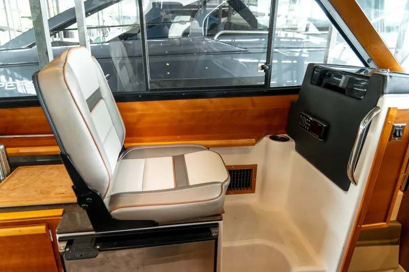 Slide: The Image of Interior of a 2020 Cutwater C28 boat, featuring a comfortable captain's chair and wooden accents. - 24