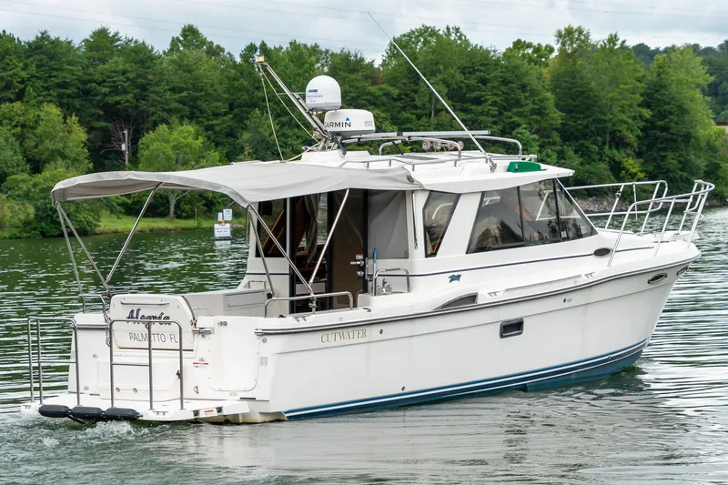 Slide: The Image of 2020 Cutwater C28 boat cruising on a serene lake with lush green trees. - 3