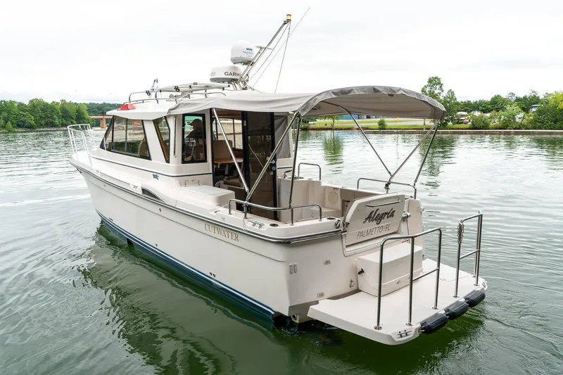 Slide: The Image of 2020 Cutwater C28 boat on calm water, featuring a spacious deck and canopy. - 5