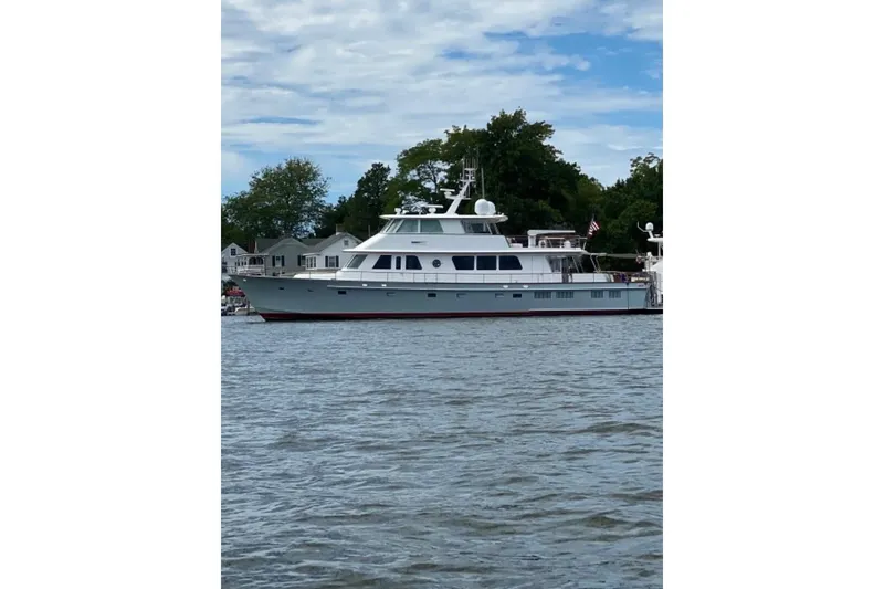 Slide: The Image of 2003 New England Boatworks Enclosed Raised Pilothouse yacht on calm water, with trees and houses in background. - 48