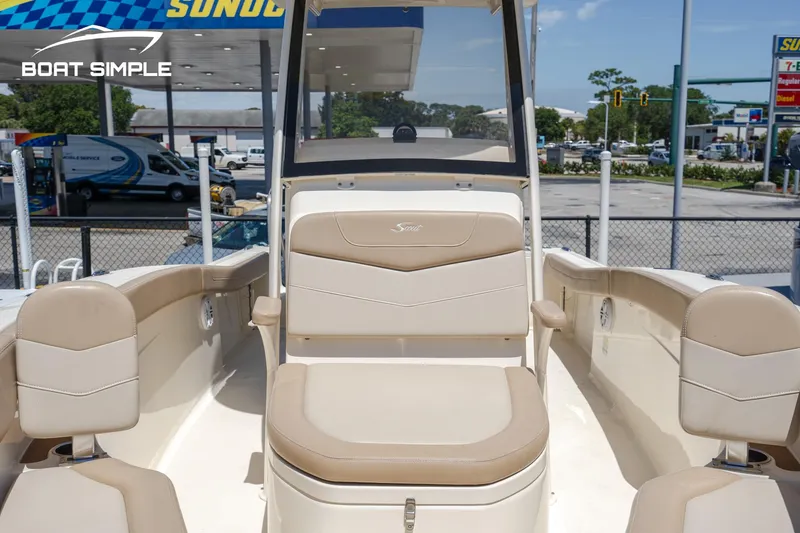 Slide: The Image of 2023 Scout 215 XSF boat interior with beige seating at a marina. - 9