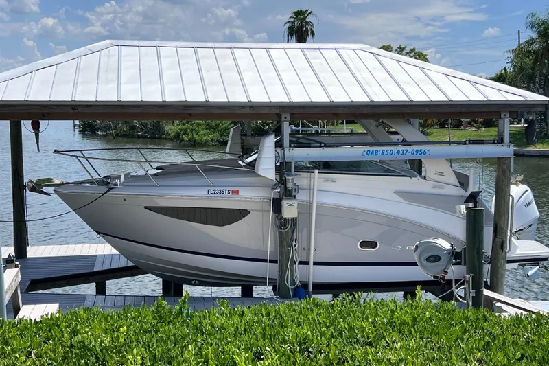 The Image of 2024 Regal 26 XO boat docked under a covered lift by the water. - 0