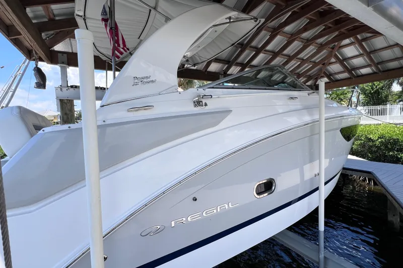 Slide: The Image of 2024 Regal 26 XO boat docked under a wooden canopy. - 10