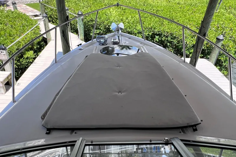 Slide: The Image of 2024 Regal 26 XO boat deck with sunpad, docked near lush greenery. - 46