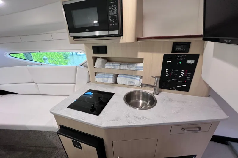 Slide: The Image of 2024 Regal 26 XO boat interior with kitchenette, microwave, sink, and seating area. - 57