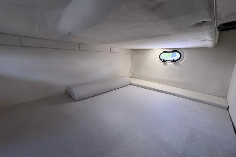 Slide: The Image of 2024 Regal 26 XO cabin interior with a small window and cushioned bed. - 61