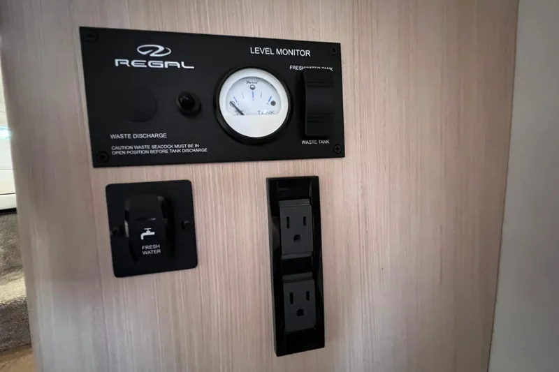 Slide: The Image of 2024 Regal 26 XO boat control panel with level monitor and outlets. - 62