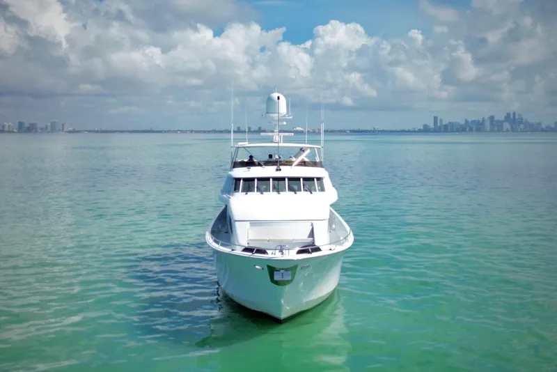 Slide: The Image of Hatteras 92 Cockpit Motor Yacht 2002 on serene turquoise waters, city skyline in background. - 2