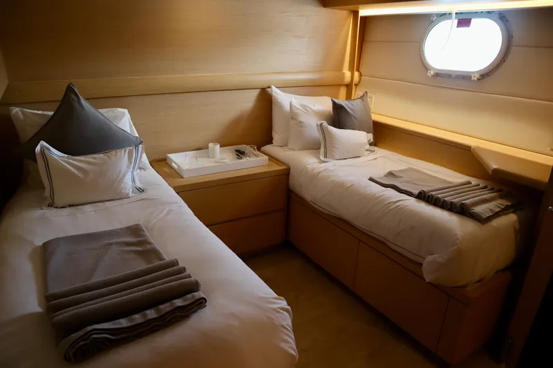 Slide: The Image of Luxurious twin cabin in 2002 Hatteras 92 Cockpit Motor Yacht, featuring elegant bedding and porthole. - 21
