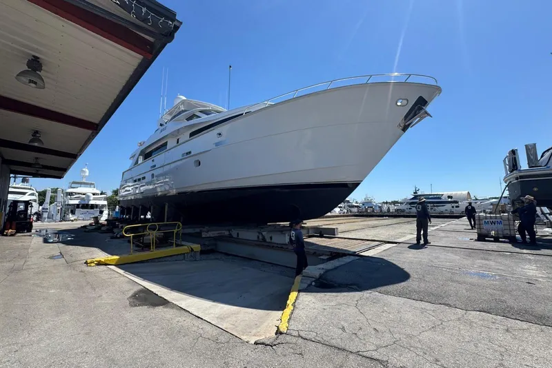 Slide: The Image of Hatteras 92 Cockpit Motor Yacht 2002 on dry dock, surrounded by workers and other boats. - 52