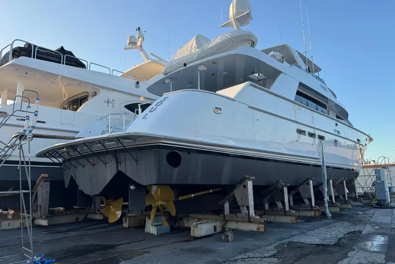 Slide: The Image of 2002 Hatteras 92 Cockpit Motor Yacht on dry dock, showcasing sleek design and propellers. - 54
