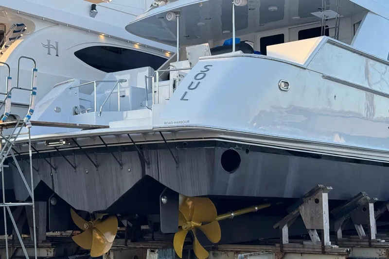 Slide: The Image of Hatteras 92 Cockpit Motor Yacht 2002 in dry dock, showcasing propellers and hull. - 56