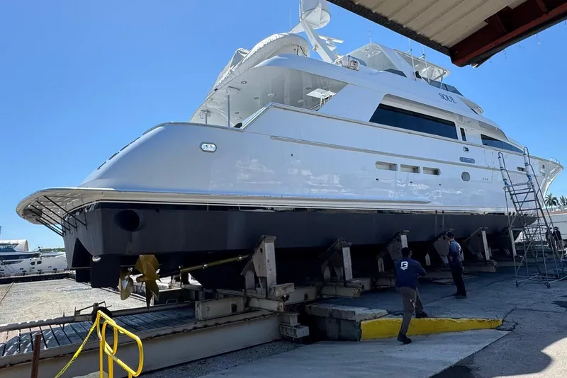 Slide: The Image of 2002 Hatteras 92 Cockpit Motor Yacht on dry dock with workers nearby. - 57