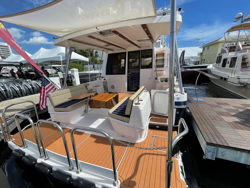 Slide: The Image of 2025 Ranger Tugs 43 Command Bridge yacht with spacious deck and seating at marina. - 1
