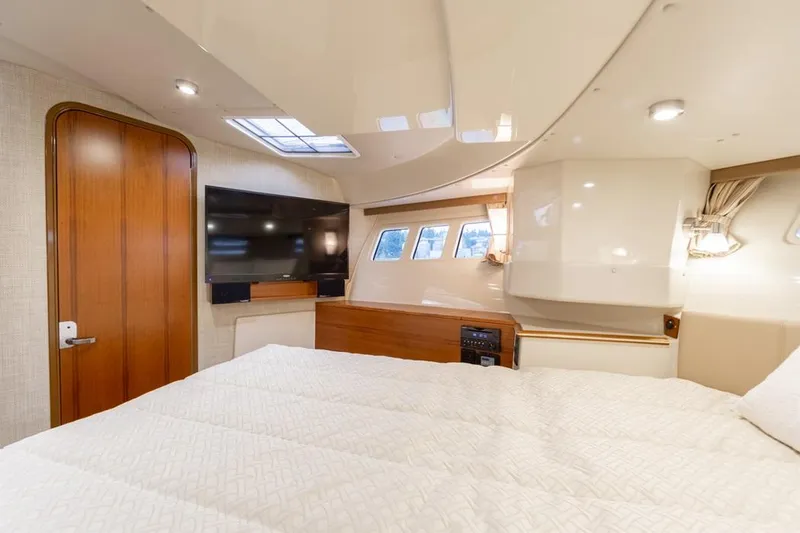 Slide: The Image of 2025 Ranger Tugs 43 Command Bridge cabin with bed, TV, and windows. - 25