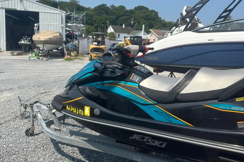 Slide: The Image of 2022 Kawasaki Jetski STX 160LX on trailer at a marina with boats in background. - 10