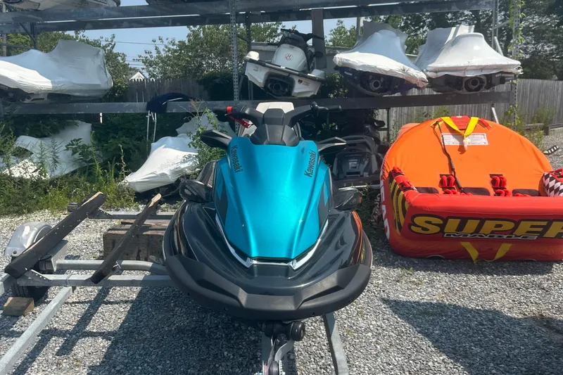 Slide: The Image of 2022 Kawasaki Jetski STX 160LX in storage, surrounded by equipment and greenery. - 3
