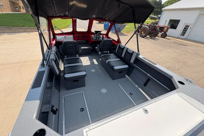 Slide: The Image of 2026 Lund 185 HG boat interior with seating and canopy, parked outdoors. - 11