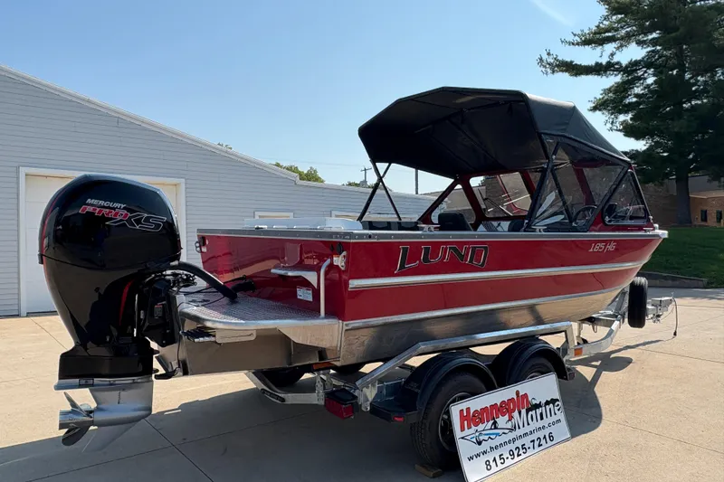 Slide: The Image of 2026 Lund 185 HG boat with Mercury Pro XS engine on trailer, parked outdoors. - 2