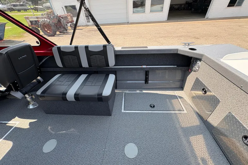 Slide: The Image of 2026 Lund 185 HG boat interior with gray and black seating, storage compartments, and a textured floor. - 23