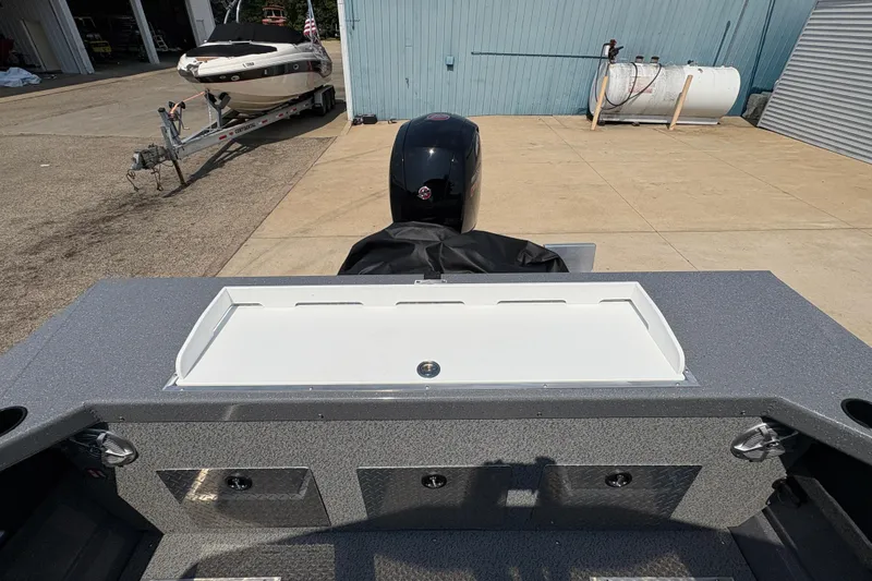 Slide: The Image of 2026 Lund 185 HG boat with motor, docked near a trailer and storage tank. - 32