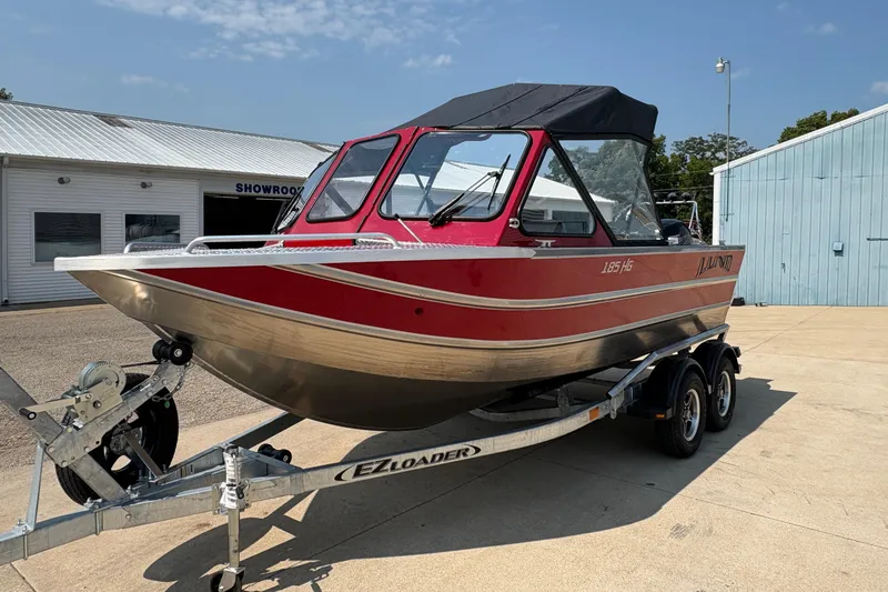 Slide: The Image of 2026 Lund 185 HG boat on trailer, red and silver, parked outside showroom. - 6
