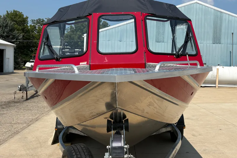 Slide: The Image of Red 2026 Lund 185 HG boat on trailer, parked outdoors near industrial buildings. - 7