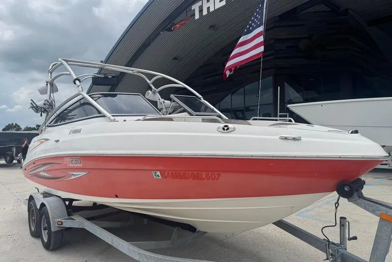 Slide: The Image of 2007 Yamaha AR 230 boat on trailer, red and white, parked near a building. - 7