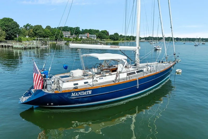 The Image of Sailing yacht Tayana 58, 1996 model, anchored in a serene harbor with lush greenery. - 0