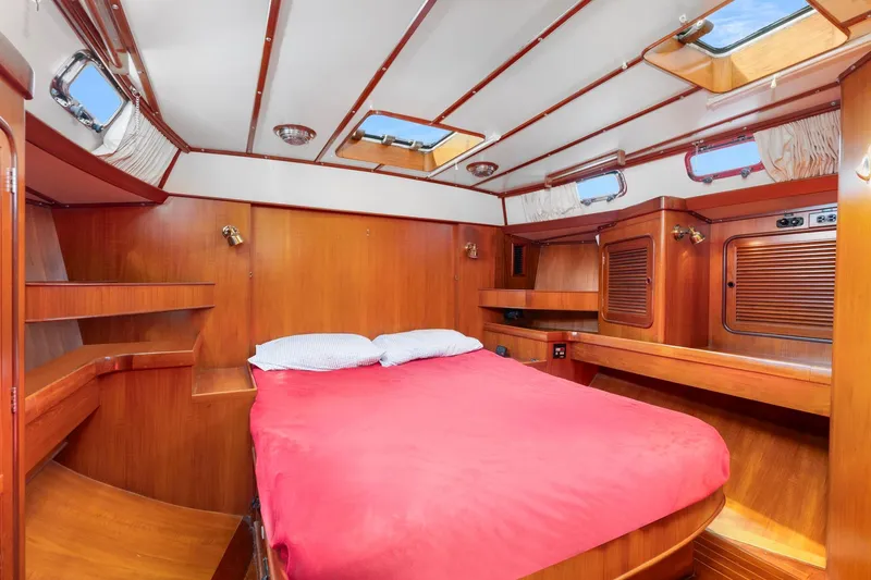 Slide: The Image of Luxurious 1996 Tayana 58 yacht cabin with wooden interior and red bedding. - 10