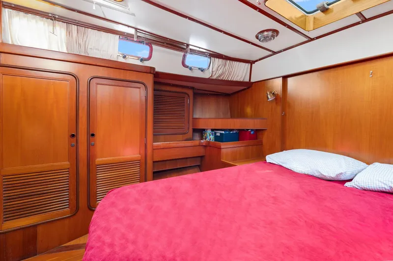 Slide: The Image of Cozy cabin interior of 1996 Tayana 58 yacht with wooden furnishings and red bedding. - 11