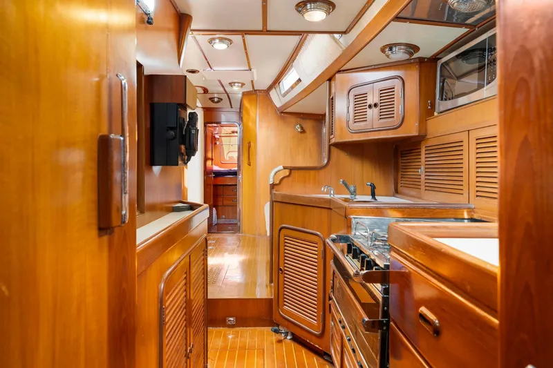 Slide: The Image of Interior of 1996 Tayana 58 yacht, featuring a wooden galley with stove and cabinets. - 7