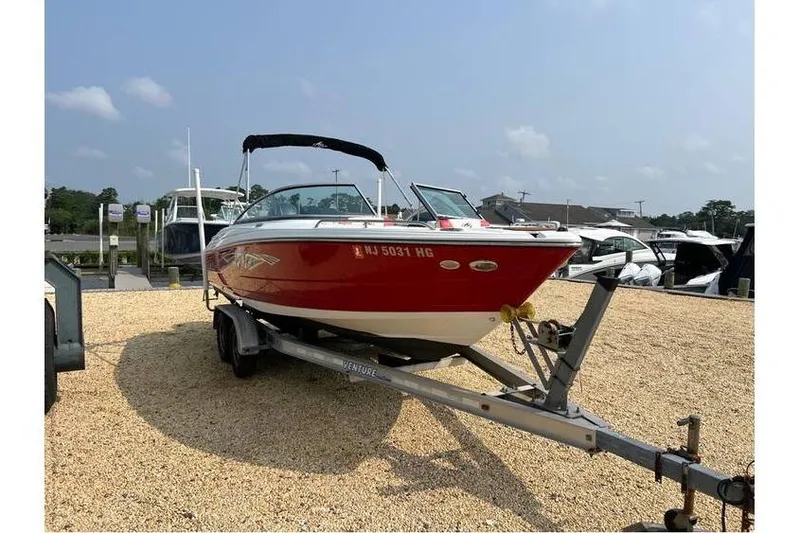 Slide: The Image of 2015 Monterey 217 Blackfin boat on trailer, red hull, parked on gravel lot. - 5
