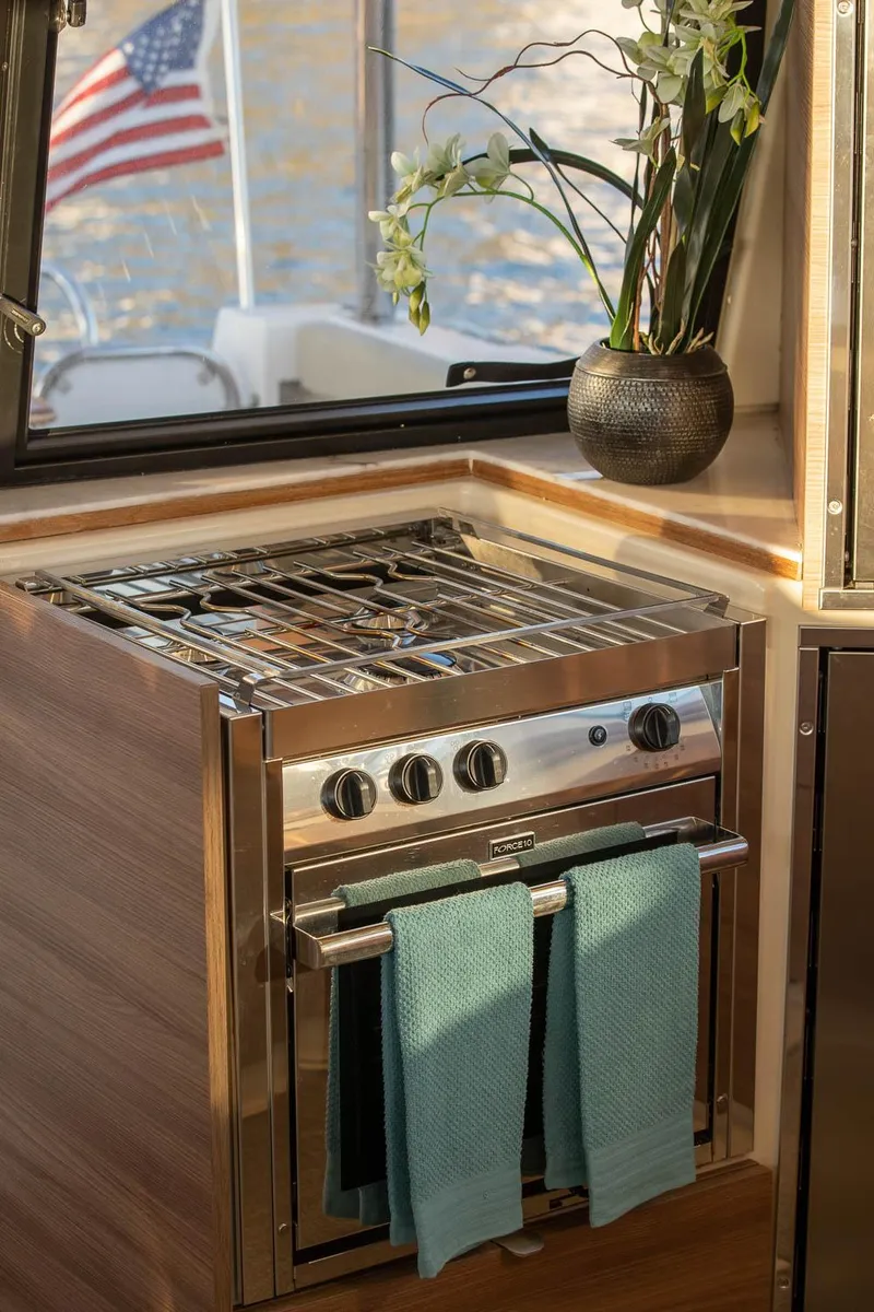 Slide: The Image of 2025 Ranger Tugs R-43 S yacht kitchen with stove, teal towels, and potted plant. - 22