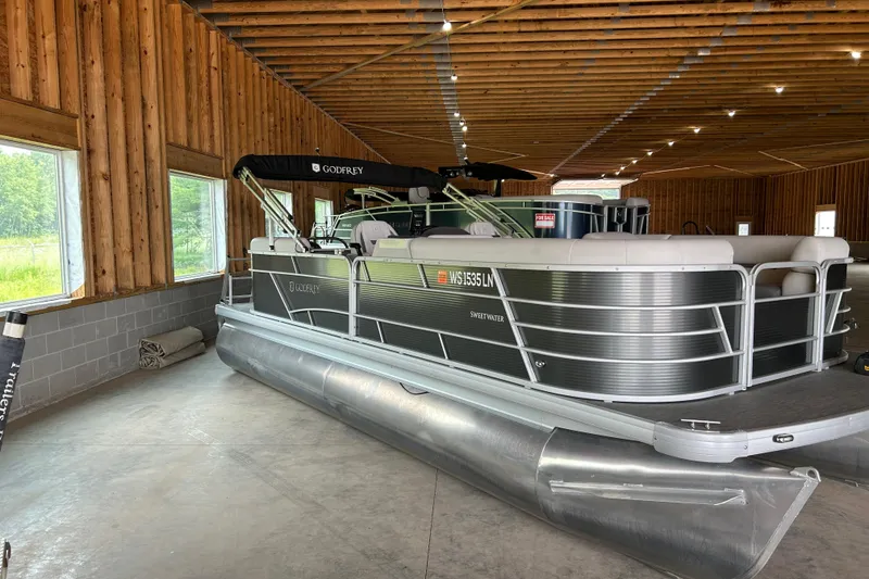 The Image of 2023 Godfrey SWEETWATER 2286 SB pontoon boat in wooden storage facility. - 1