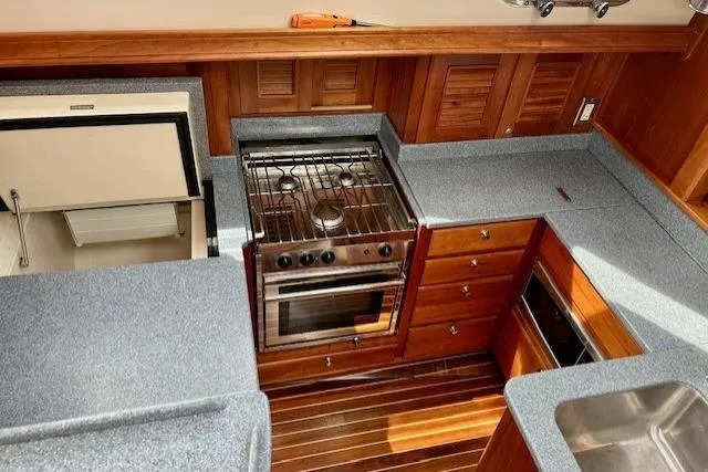 Slide: The Image of 2016 Gozzard 41 RC yacht kitchen with stove, fridge, and wooden cabinetry. - 21